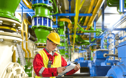 Man wearing safety gear reviewing a clipboard on a job site